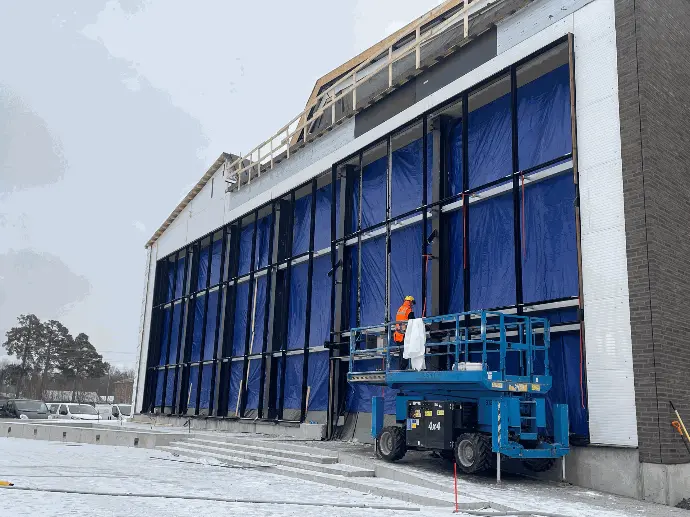 Rakenteilla oleva kohde, jossa julkisivuun asennetaan suuria elementtejä.