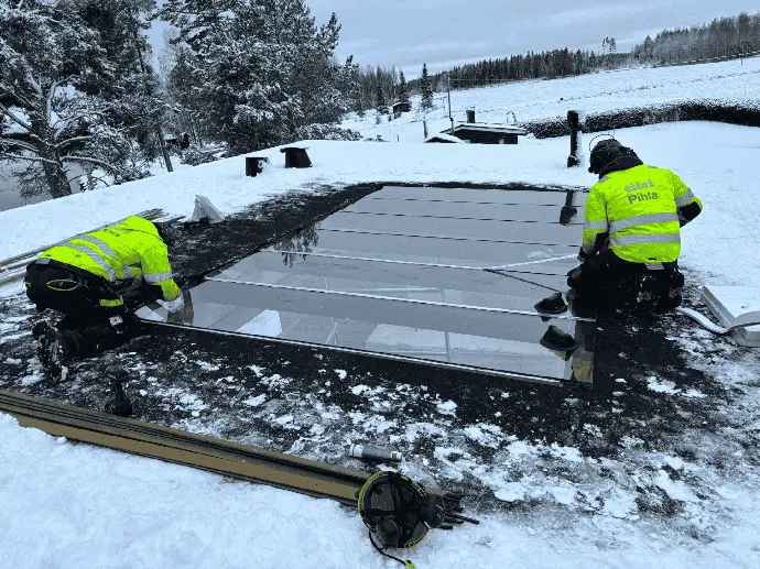  Talvinen työmaa, jossa asennetaan lasipintoja ulkotiloihin.