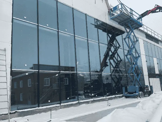 Nostoalustalta tehtävä lasiasennus liiketilan ulkoseinään.