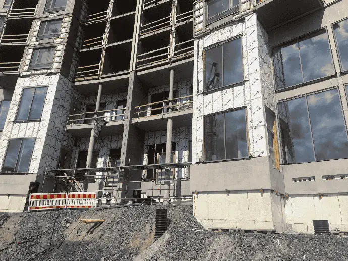 Keskeneräinen rakennus, jossa käynnissä ikkuna-asennuksia.