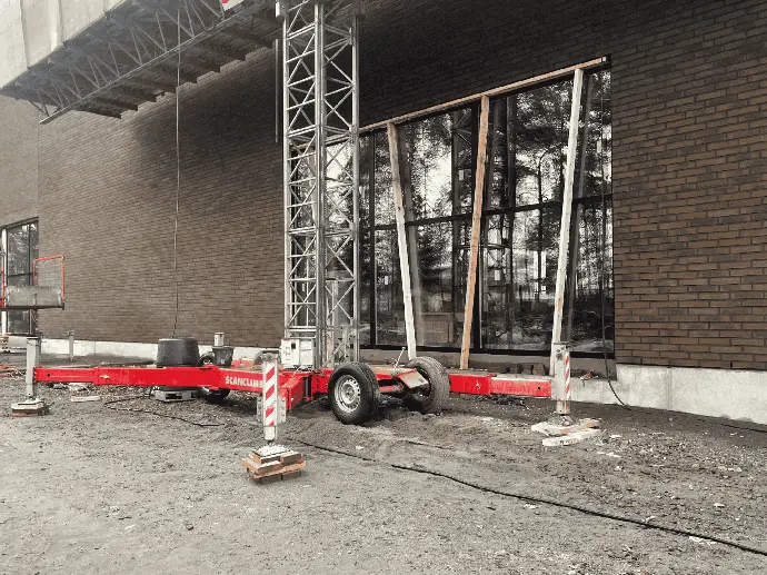 Rakennustyömaa, jossa nostokalustoa käytetään ikkunoiden asentamiseen.
