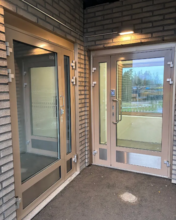 Lasinen sisäänkäynti ovineen ja ikkunoineen.